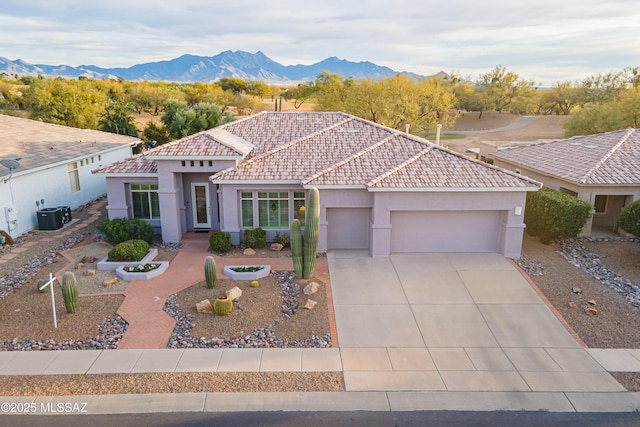 mediterranean / spanish house with a mountain view, a garage, and central AC unit