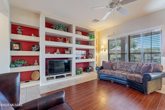 living room with built in shelves and ceiling fan