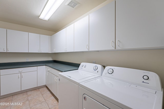 laundry area featuring separate washer and dryer, light tile patterned floors, and cabinets