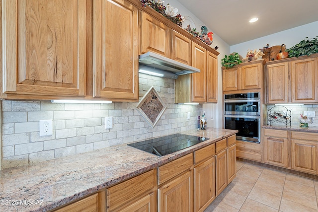 kitchen featuring black electric stovetop, decorative backsplash, light tile patterned floors, double oven, and light stone counters