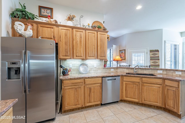 kitchen with sink, stainless steel appliances, light stone counters, backsplash, and kitchen peninsula