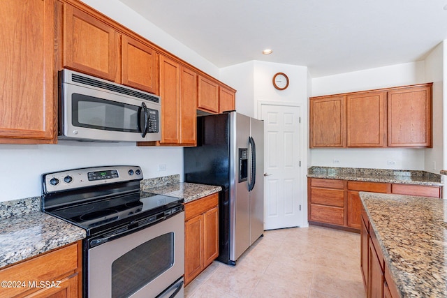 kitchen with light stone countertops, light tile patterned flooring, and appliances with stainless steel finishes