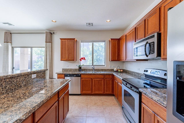 kitchen with dark stone countertops, a wealth of natural light, sink, and appliances with stainless steel finishes