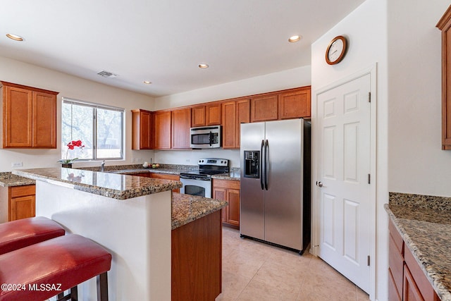 kitchen featuring a center island, stone counters, a kitchen breakfast bar, light tile patterned floors, and stainless steel appliances