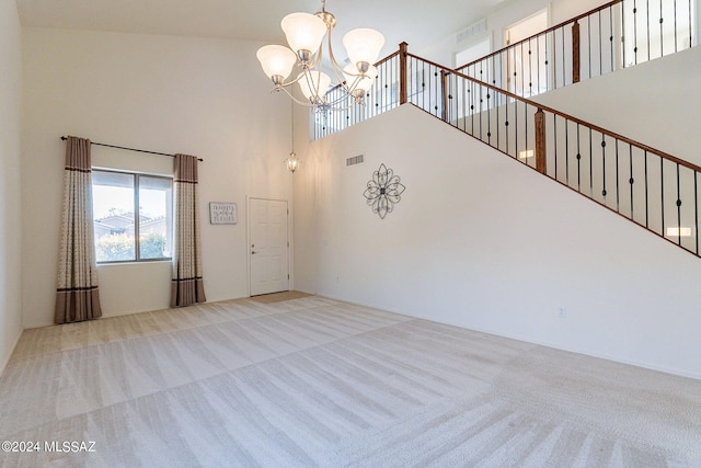 interior space with a towering ceiling, light carpet, and an inviting chandelier