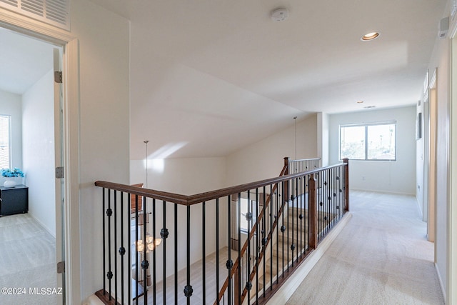 hallway with light colored carpet and lofted ceiling