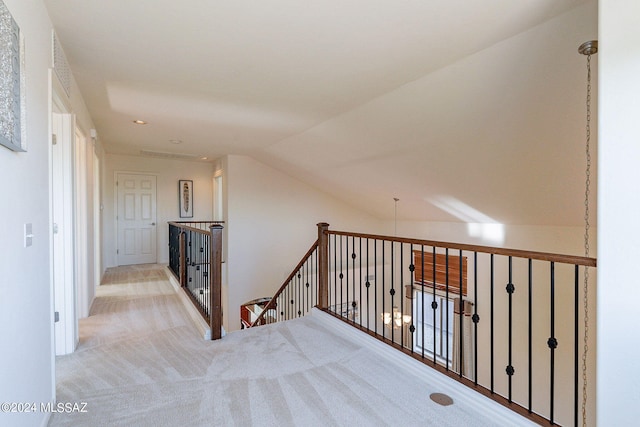 hallway with light colored carpet and vaulted ceiling