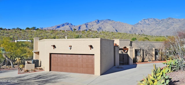 view of front facade with central AC unit, a mountain view, a garage, and an outdoor structure