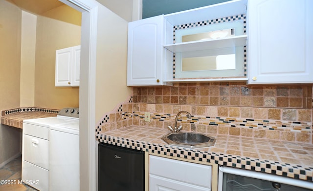 kitchen with tasteful backsplash, washing machine and dryer, sink, and white cabinets