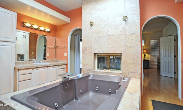 bathroom with hardwood / wood-style floors, vanity, and tiled tub