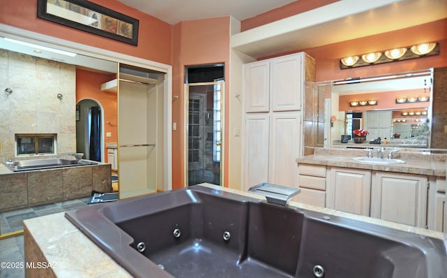 bathroom featuring vanity, independent shower and bath, and a tiled fireplace