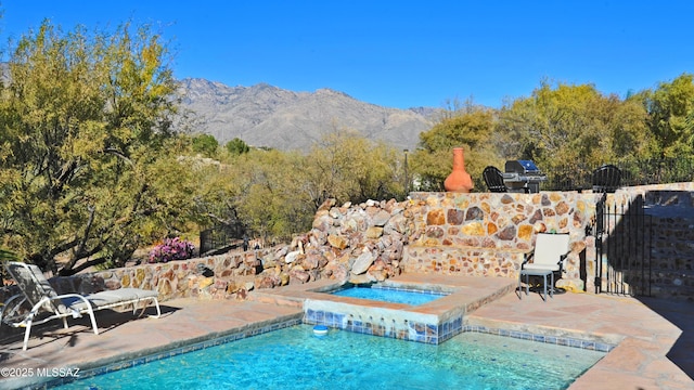 view of swimming pool featuring a mountain view and an in ground hot tub