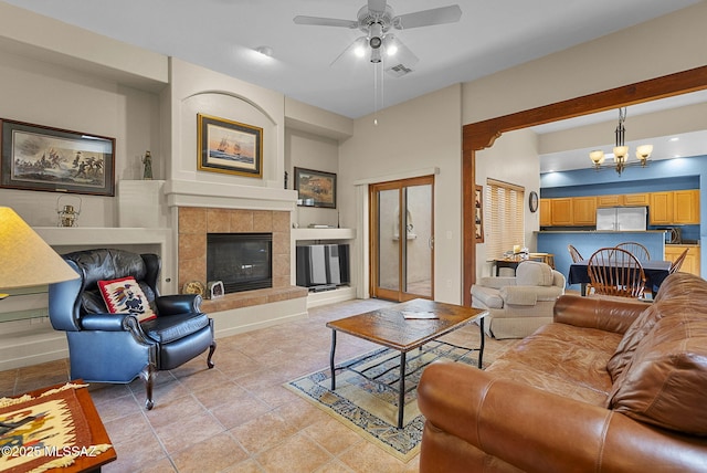 tiled living room with ceiling fan with notable chandelier, built in features, and a fireplace