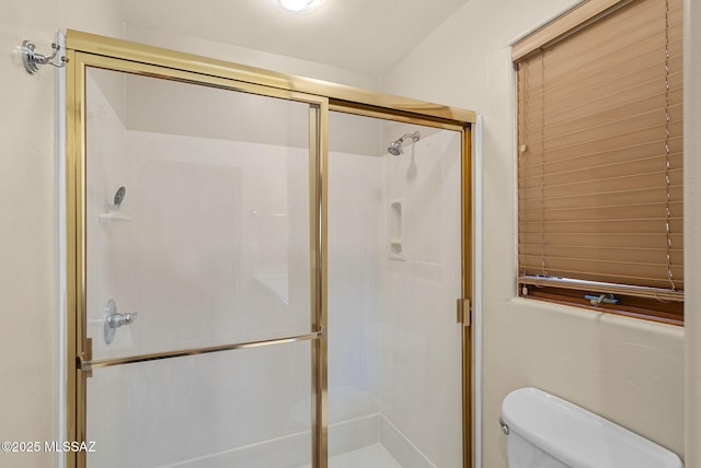 bathroom featuring toilet and a shower with shower door