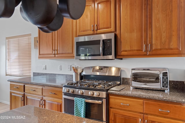 kitchen featuring dark stone countertops and appliances with stainless steel finishes