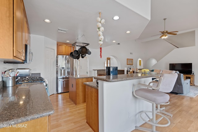 kitchen featuring ceiling fan, an island with sink, dark stone counters, and stainless steel appliances