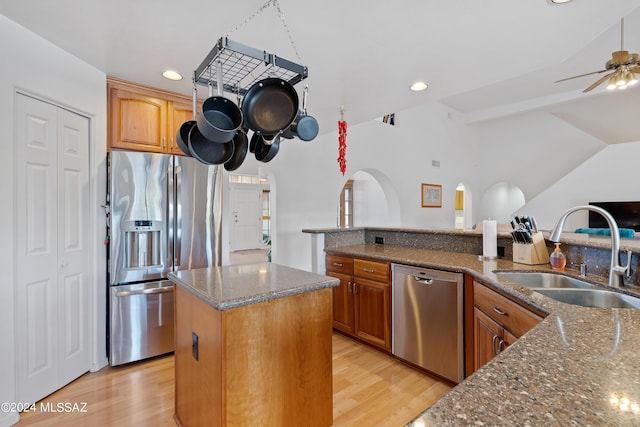 kitchen with a kitchen island with sink, sink, ceiling fan, dark stone countertops, and appliances with stainless steel finishes