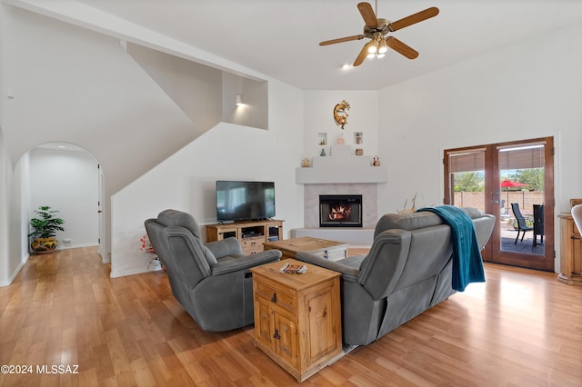 living room featuring a towering ceiling, light wood-type flooring, and ceiling fan