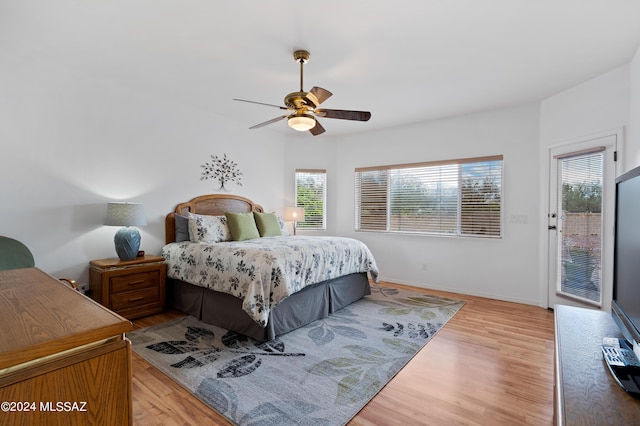 bedroom featuring ceiling fan, access to exterior, light hardwood / wood-style flooring, and multiple windows