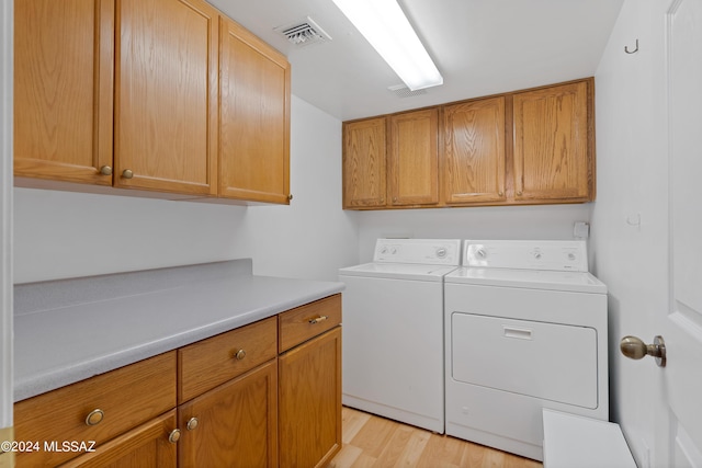 laundry room with cabinets, light hardwood / wood-style floors, and washer and dryer