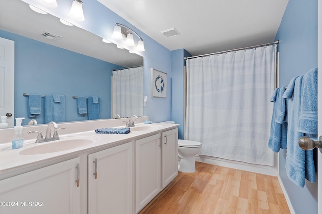 full bathroom with hardwood / wood-style floors, vanity, toilet, and shower / tub combo with curtain