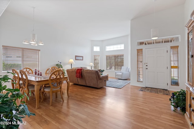 entrance foyer with light wood-type flooring, a high ceiling, and an inviting chandelier