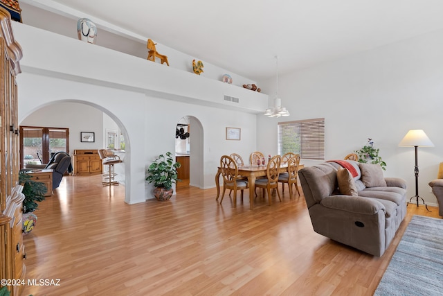 living room featuring a wealth of natural light, light hardwood / wood-style flooring, and an inviting chandelier