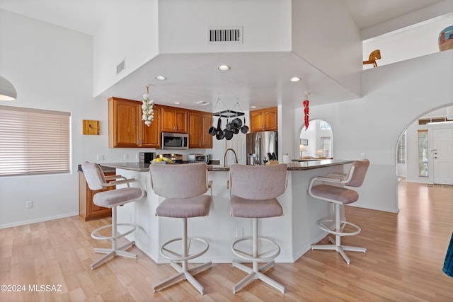 kitchen with kitchen peninsula, a kitchen breakfast bar, stainless steel appliances, and light hardwood / wood-style floors