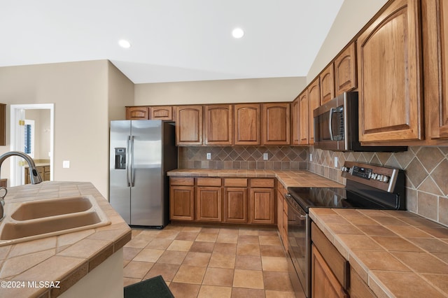 kitchen with backsplash, tile counters, stainless steel appliances, and sink