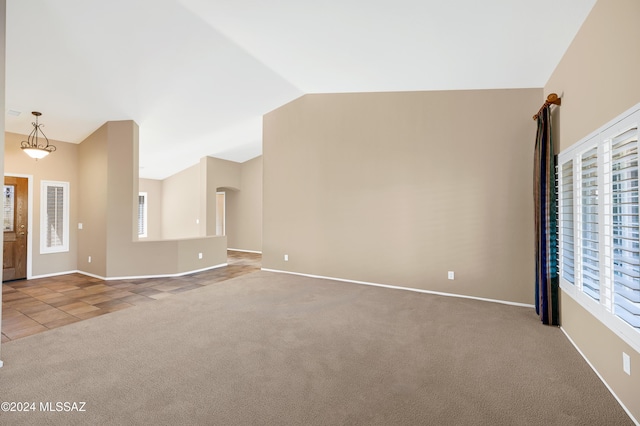 unfurnished living room featuring a wealth of natural light, carpet floors, and vaulted ceiling