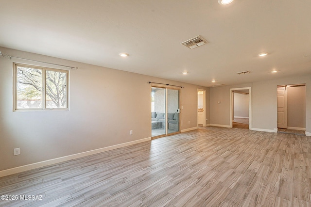 unfurnished room with a barn door, plenty of natural light, and light hardwood / wood-style floors