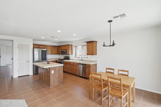 kitchen featuring sink, stainless steel appliances, tile patterned floors, pendant lighting, and a kitchen island