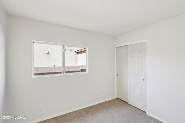 unfurnished bedroom with light colored carpet and a closet