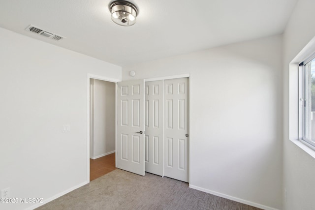 unfurnished bedroom featuring light colored carpet and a closet