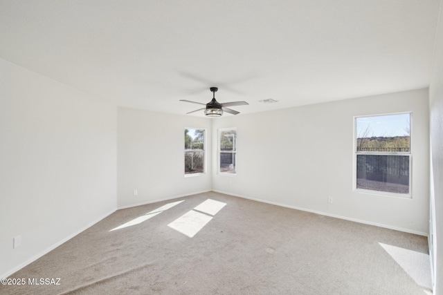 unfurnished room featuring light colored carpet, a wealth of natural light, and ceiling fan