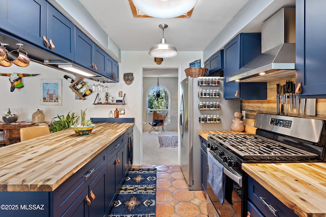 kitchen featuring blue cabinetry, stainless steel range with gas stovetop, butcher block countertops, and wall chimney range hood