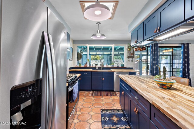 kitchen with a peninsula, blue cabinetry, visible vents, and wooden counters