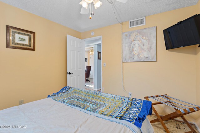 bedroom with a textured ceiling, ceiling fan, and baseboards