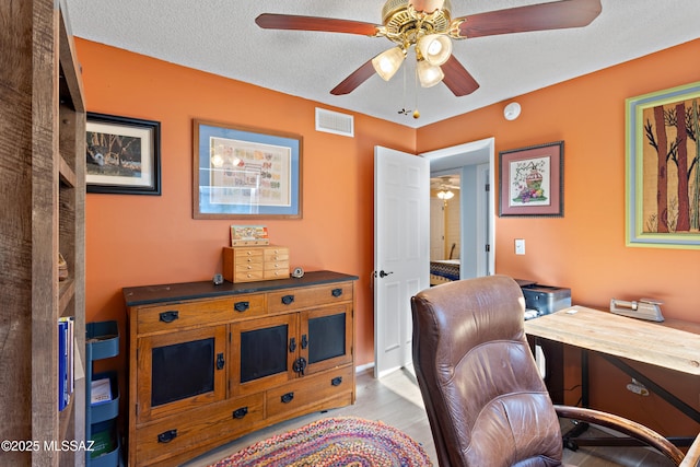 home office with light wood-type flooring, a textured ceiling, and ceiling fan