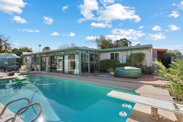 view of pool with a patio and a diving board