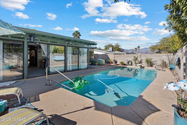 back of house featuring a fenced in pool, a sunroom, and a patio area
