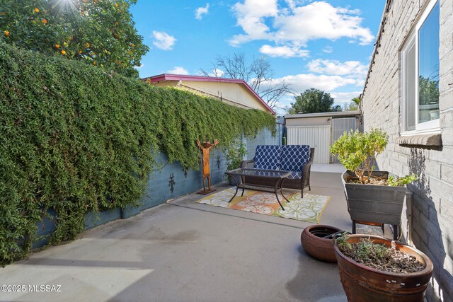 view of patio featuring a storage unit, area for grilling, a fenced backyard, an outdoor structure, and a fire pit
