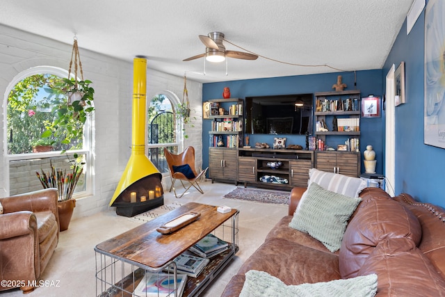 living room with ceiling fan, a wood stove, and a textured ceiling