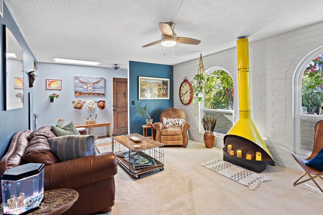 living room featuring ceiling fan, carpet, a healthy amount of sunlight, and a wood stove