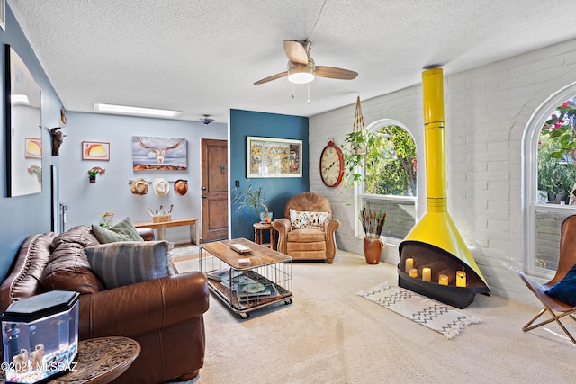 living room featuring plenty of natural light, carpet, a textured ceiling, and a wood stove