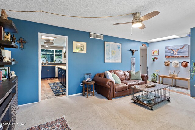 carpeted living room featuring a ceiling fan, a textured ceiling, a wood stove, and brick wall