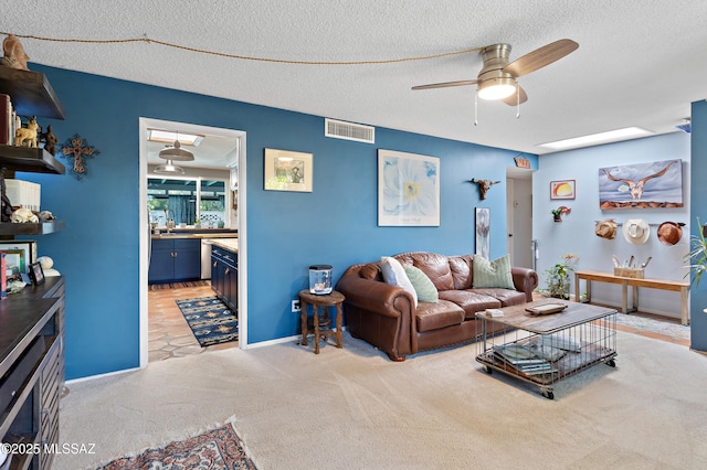 living room with light carpet, ceiling fan, and a textured ceiling