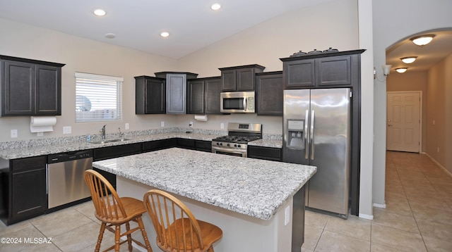 kitchen featuring a center island, a kitchen breakfast bar, sink, light tile patterned flooring, and stainless steel appliances