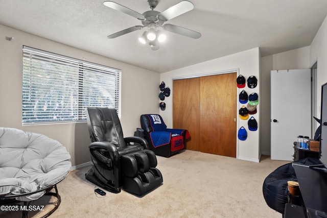 living area featuring ceiling fan, carpet, and a textured ceiling