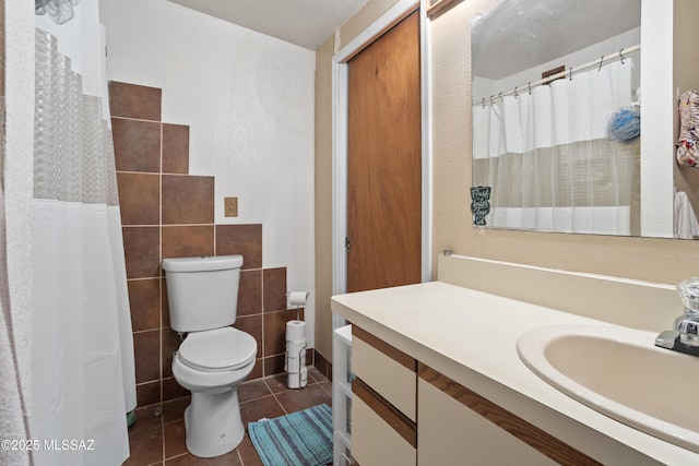 bathroom with tile walls, vanity, curtained shower, tile patterned floors, and toilet